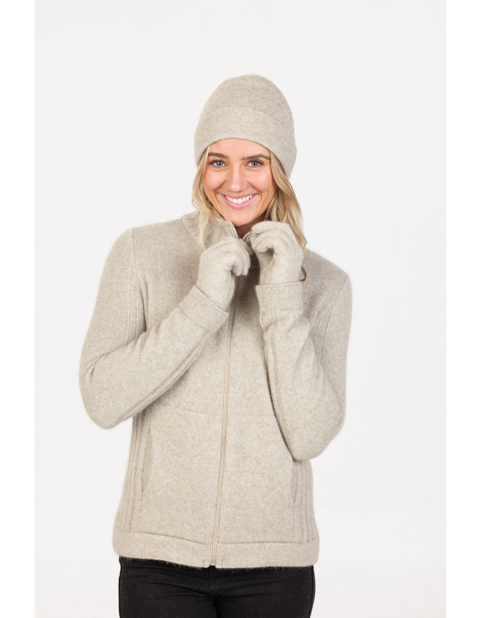 Woman wearing a beige jacket, beanie, and gloves on a white background