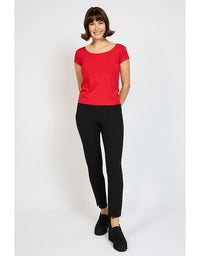 Woman wearing a red top and black pants on a white background