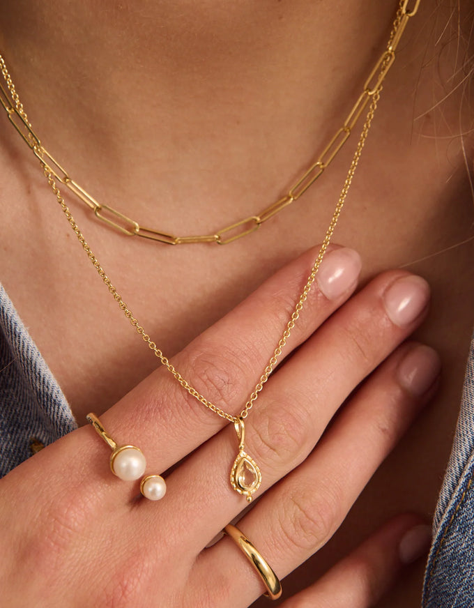 Gold jewelry including necklaces and rings on a person's hand and neck.