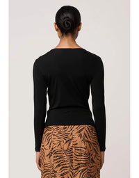 Person wearing a black long-sleeve top and a brown skirt with a leaf pattern on a light gray background