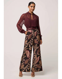 Woman wearing a burgundy blouse and patterned pants on a white background