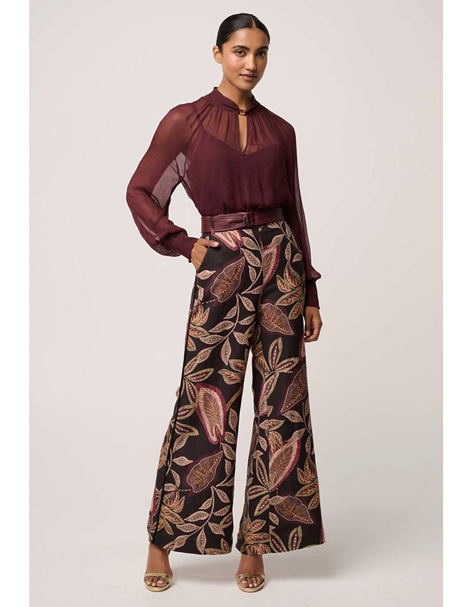 Woman wearing a burgundy blouse and patterned pants on a white background