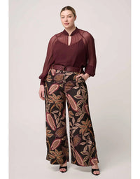Woman wearing a burgundy blouse and patterned pants on a white background