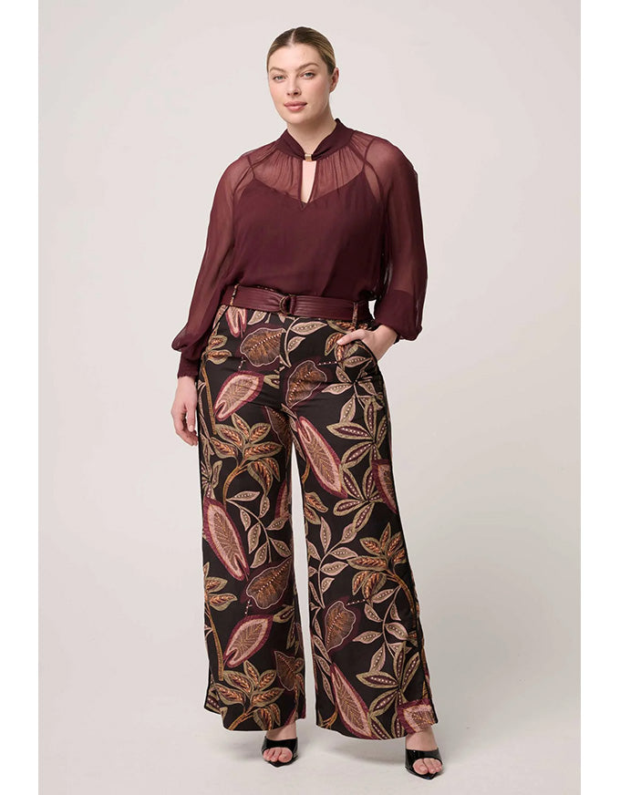 Woman wearing a burgundy blouse and patterned pants on a white background