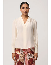 Woman wearing a cream blouse with a plain background