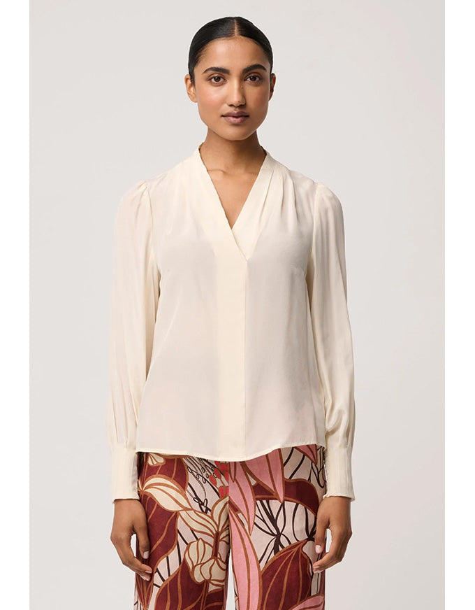 Woman wearing a cream blouse with a plain background
