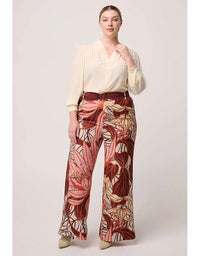 Woman wearing a cream blouse and patterned pants on a light gray background