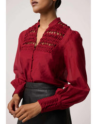 Red blouse with intricate detailing worn by a person on a plain background
