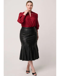 Woman wearing a red blouse and black leather skirt on a light background