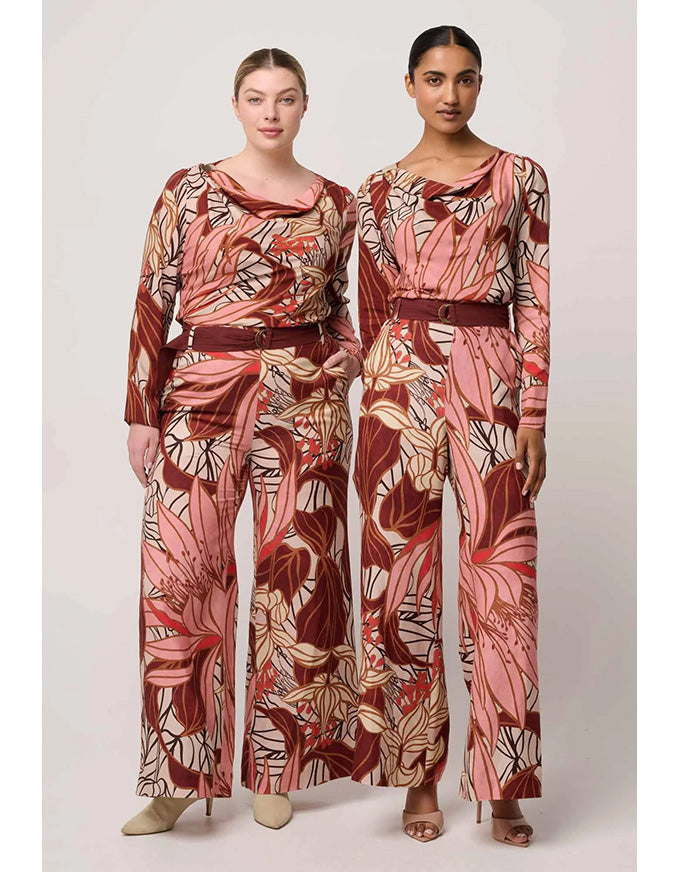 Two women wearing matching floral-patterned outfits on a plain background