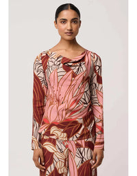 Woman wearing a long-sleeve top with a floral pattern on a plain background