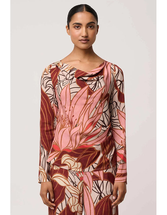 Woman wearing a long-sleeve top with a floral pattern on a plain background