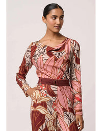 Woman wearing a patterned dress with a belt on a plain background