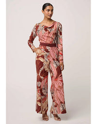 Woman wearing a patterned jumpsuit on a plain background