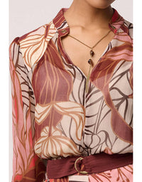 Mannequin wearing a patterned blouse with a necklace on a white background