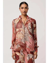 Woman wearing a patterned blouse with a neutral background