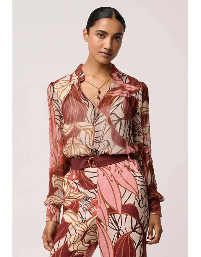 Woman wearing a patterned outfit with a belt on a plain background
