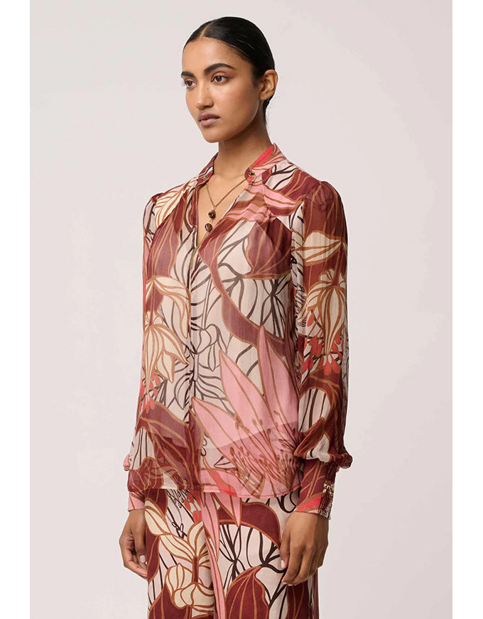 Woman wearing a patterned blouse against a plain background
