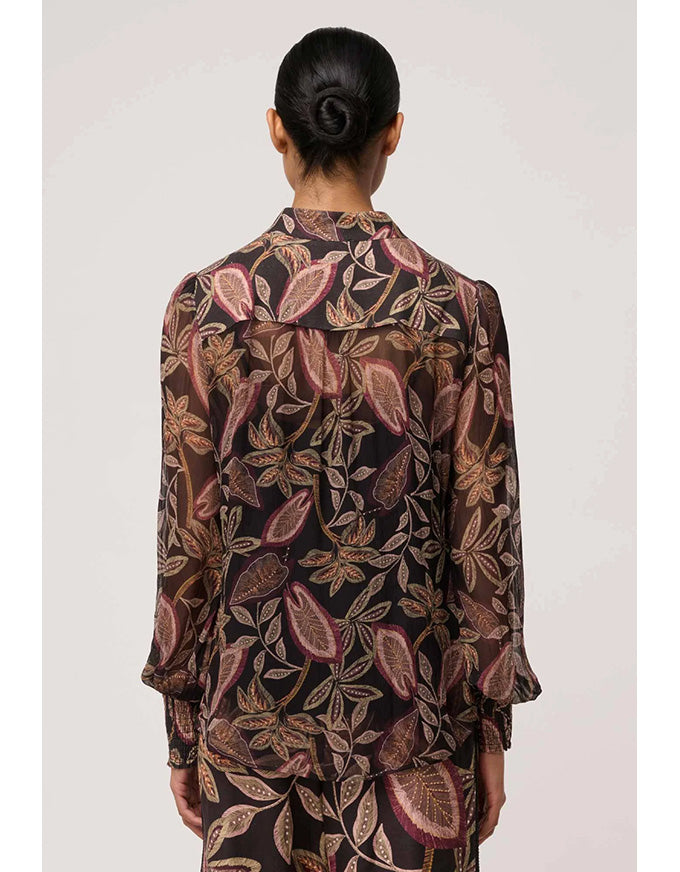 Person wearing a patterned shirt with a plain background