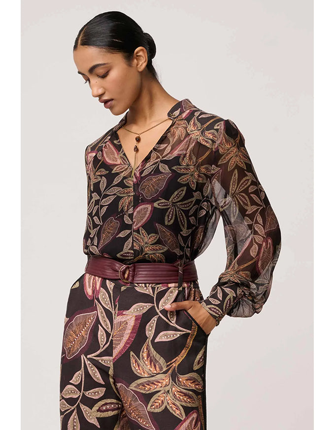 Woman wearing a patterned outfit with a belt on a white background