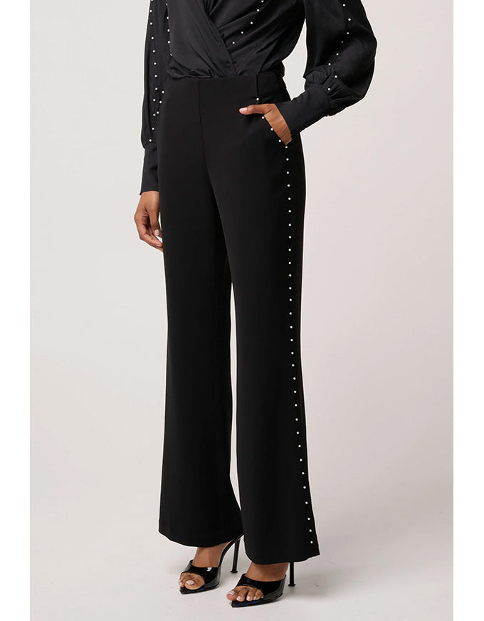 Black outfit with studded details on a light gray background