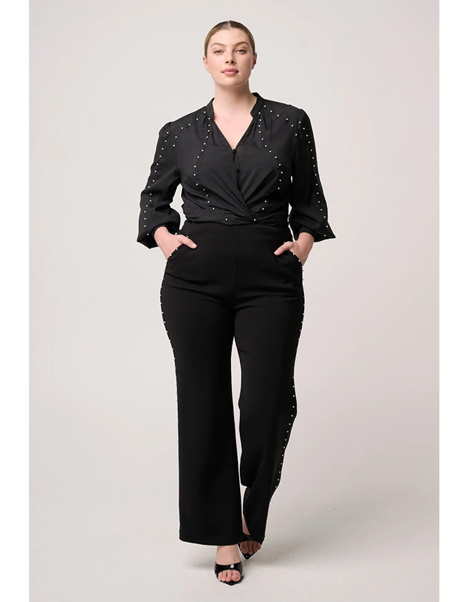 Woman wearing a black outfit with embellishments on a plain background