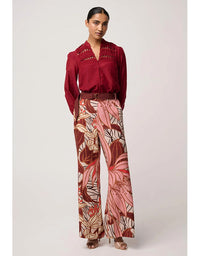 Woman wearing a red blouse and patterned pants on a white background