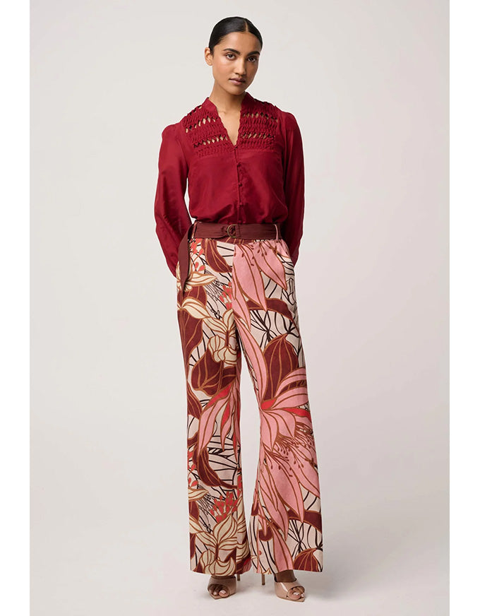 Woman wearing a red blouse and patterned pants on a white background