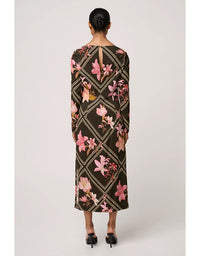 Woman wearing a long floral dress with geometric pattern on a white background