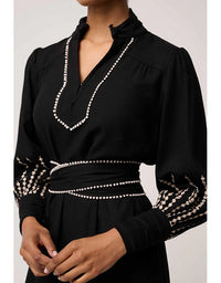 Black blouse with decorative white patterns on a plain background