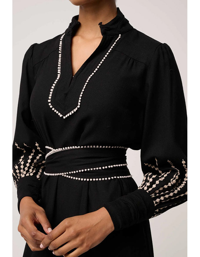 Black blouse with decorative white patterns on a plain background