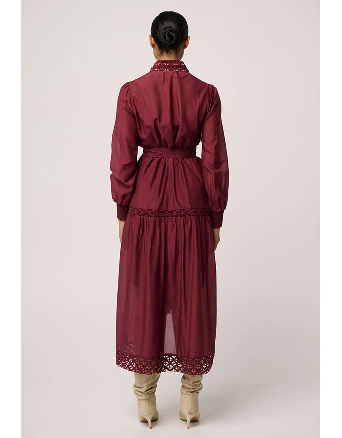 Maroon dress with lace details worn by a person on a light gray background