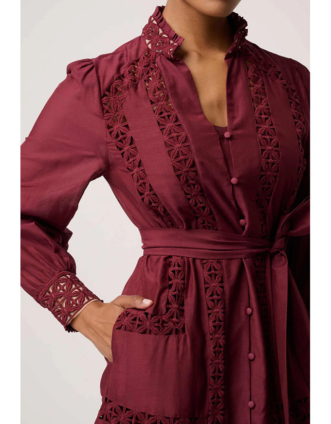 Maroon dress with intricate lace detailing on a white background