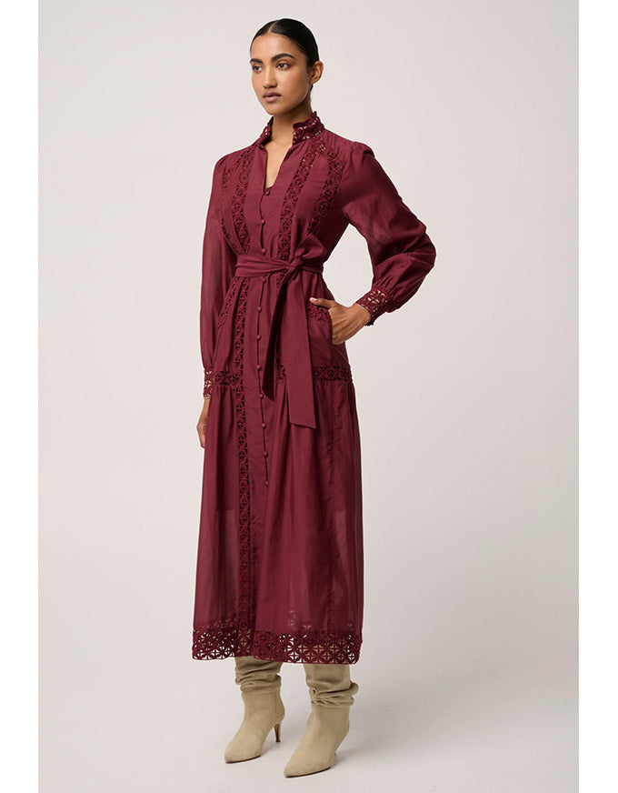 Woman wearing a burgundy dress with lace details on a white background