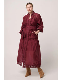Woman wearing a burgundy dress with lace details on a white background