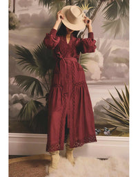 Person wearing a burgundy dress with lace details in a room with decorative wall art.