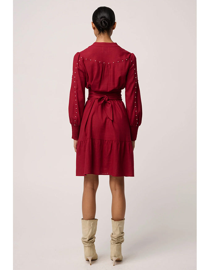 Red dress with long sleeves and a belt worn by a person on a white background