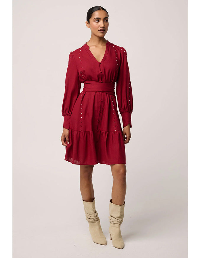 Woman wearing a red dress with long sleeves and beige boots on a white background