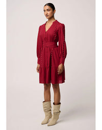 Woman wearing a red dress with long sleeves and beige boots on a white background
