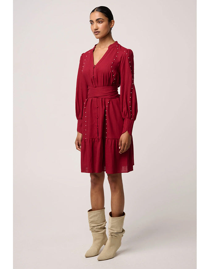 Woman wearing a red dress with long sleeves and beige boots on a white background
