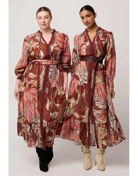 Two women wearing patterned dresses standing side by side on a white background