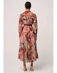 Woman wearing a long, patterned dress on a plain background