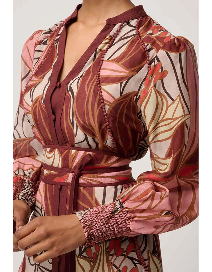 Patterned top with long sleeves and a belt on a plain background