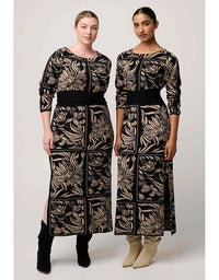 Two women wearing matching black and gold patterned dresses on a white background