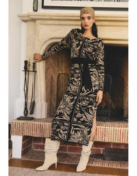 Woman in a patterned dress standing in front of a fireplace