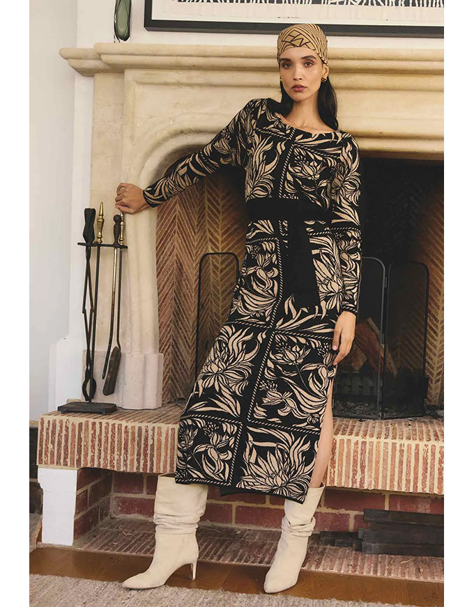 Woman in a patterned dress standing in front of a fireplace