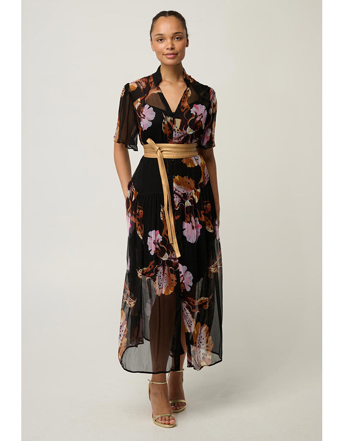 A woman models a black midi wrap dress with a vibrant floral print in pink, purple, and orange, featuring short flutter sleeves, a V-neckline, and a tan tie belt at the waist.