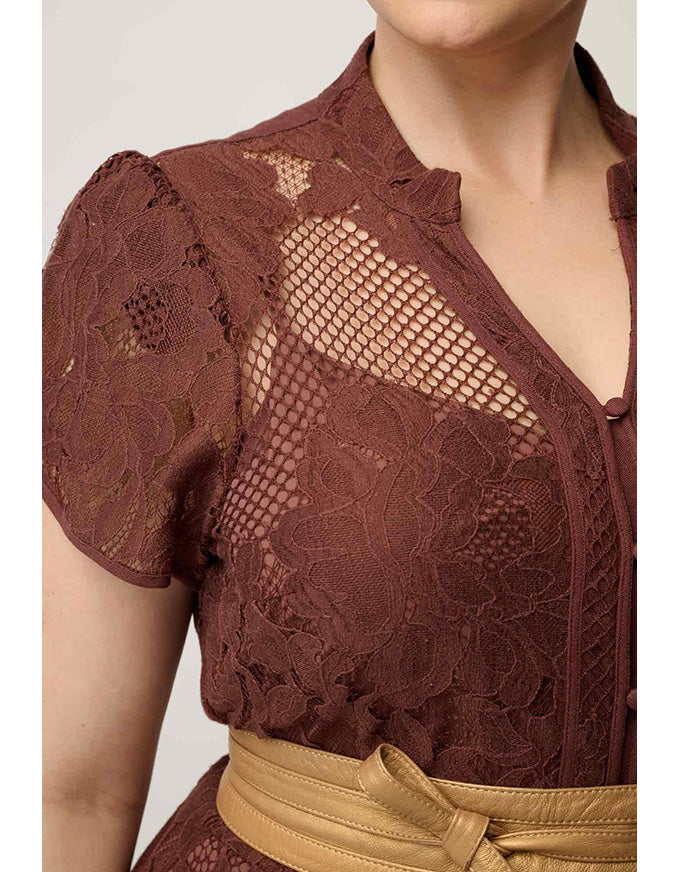 Close-up of a woman wearing a brown lace short-sleeve top with a tan belt, cropped from the lower face to the waist against a plain light background.