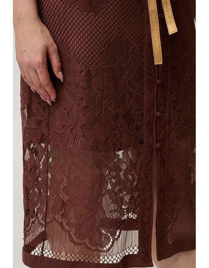 Close-up of a dark brown lace dress or skirt with a sheer mesh overlay, floral lace pattern, scalloped hem, and a gold drawstring tie.