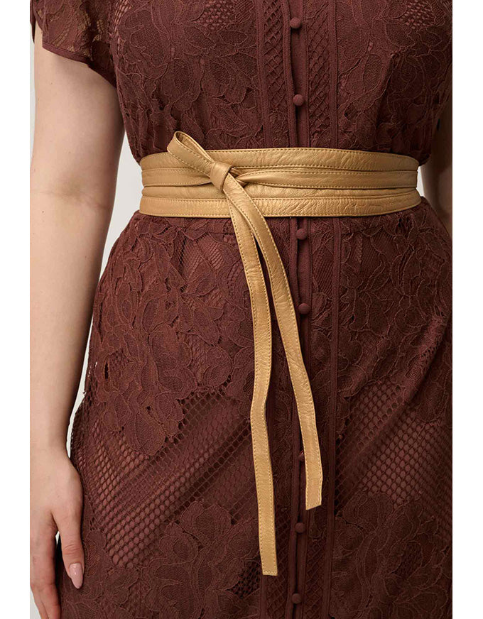 A close-up of a woman wearing a dark brown lace dress with a wide tan faux-leather waist tie belt at the waist.